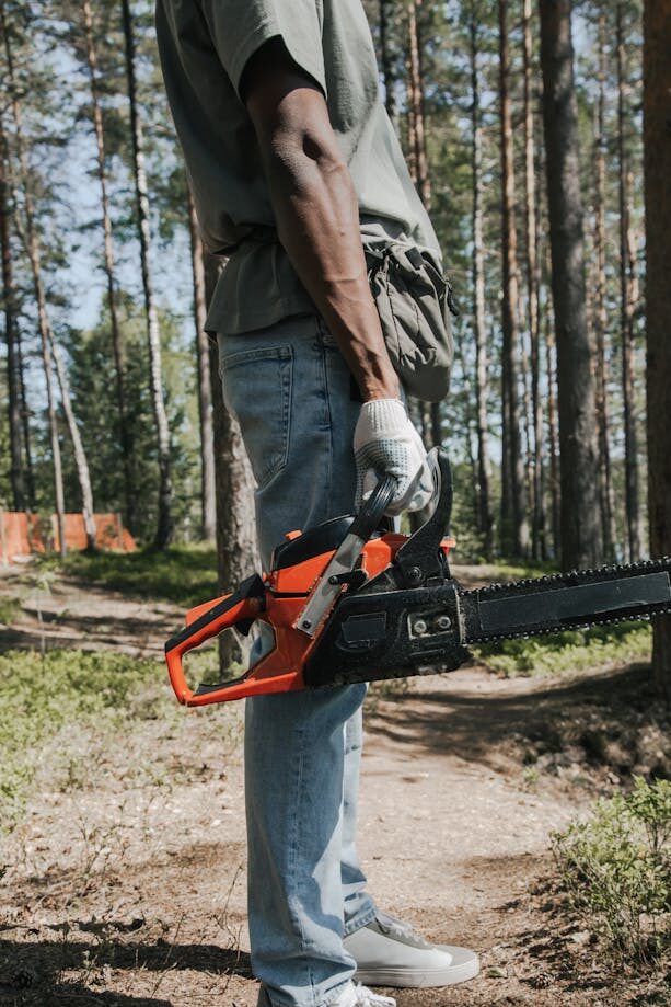 A Person in Denim Pants Holding a Chainsaw